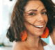 a woman with orange earrings smiling at the camera